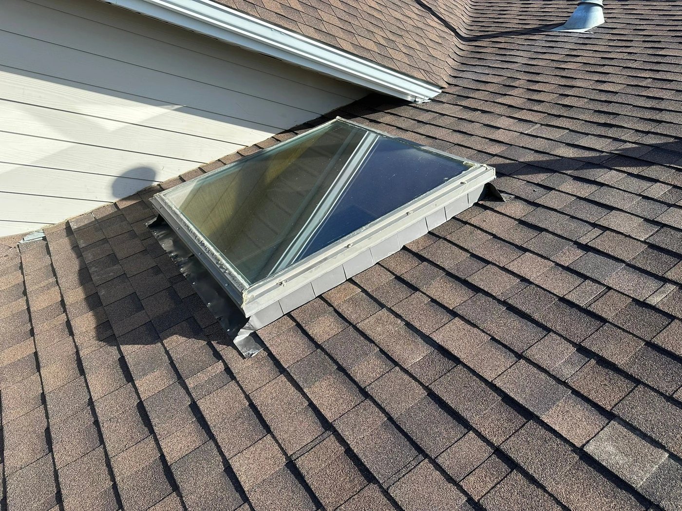 Skylight installed within a finished asphalt shingle roof