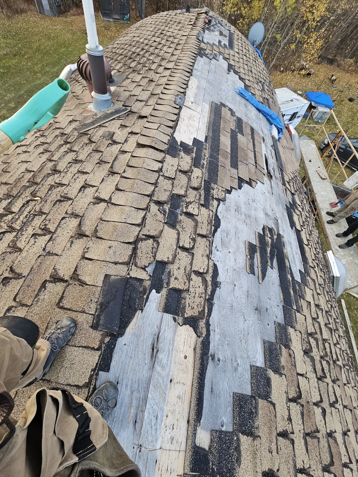 Worn asphalt shingles and exposed decking near a roof vent