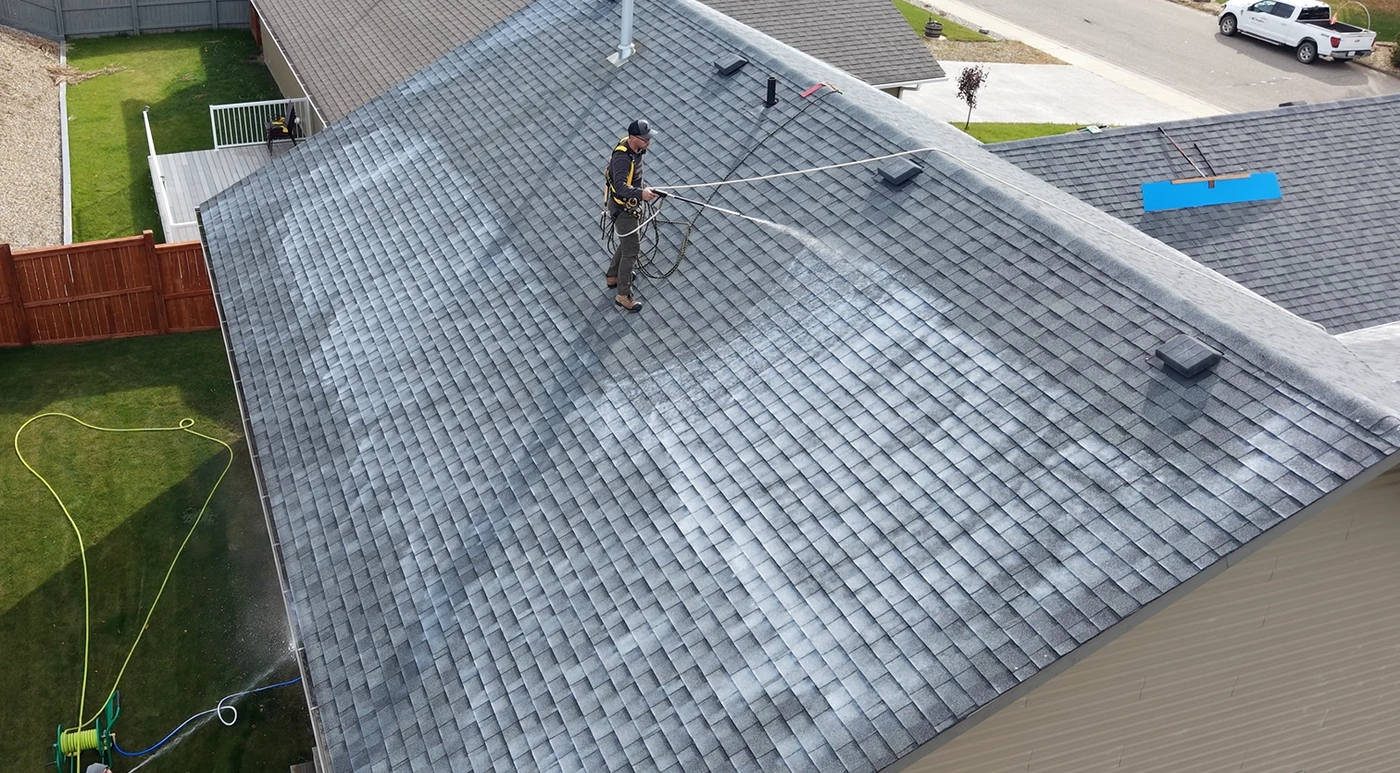 Raptor crew member spraying roof rejuvenation treatment on an asphalt shingle roof