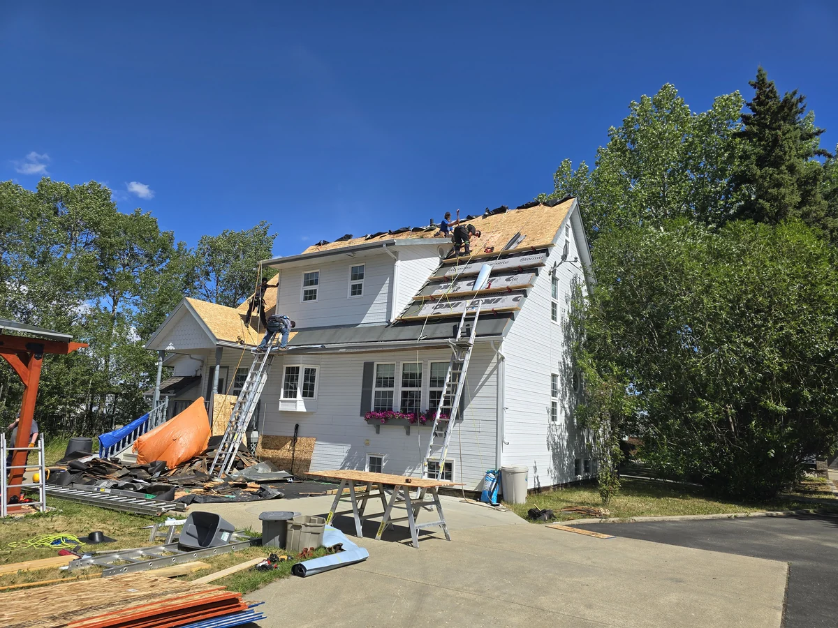 Roof replacement underway on a tall white house