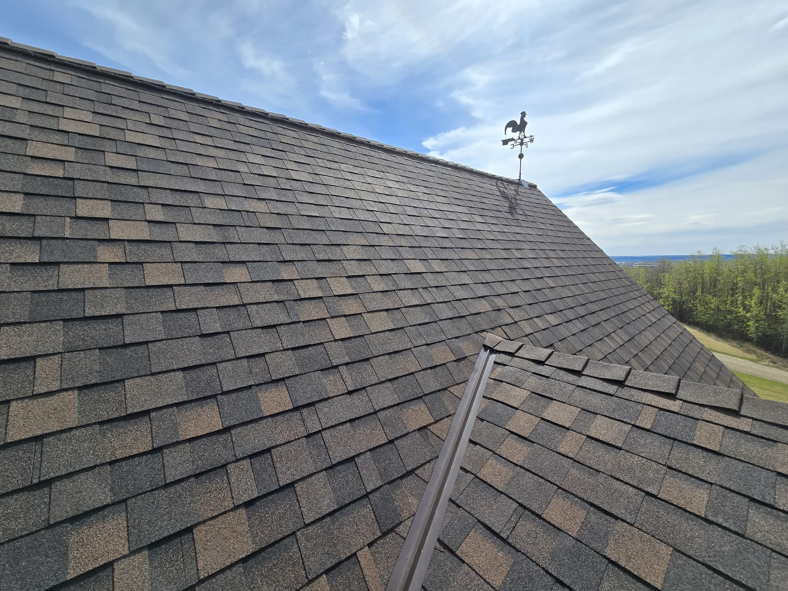 Asphalt shingle roof with a weather vane at the ridge